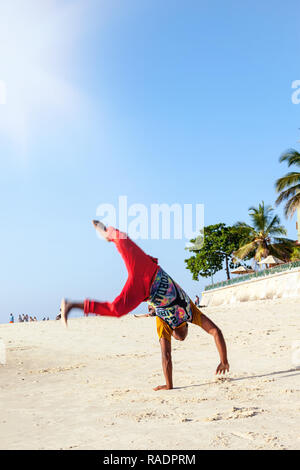 Stone Town, Zanzibar, Tanzania - January 7, 2017. Handsome man doing flips on beach. Stock Photo
