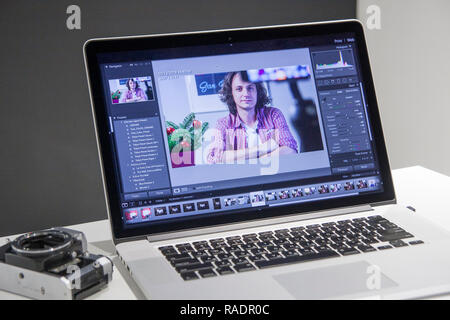 Professional photo editor working on laptop in special colorgrade software to edit new photos from his camera Stock Photo