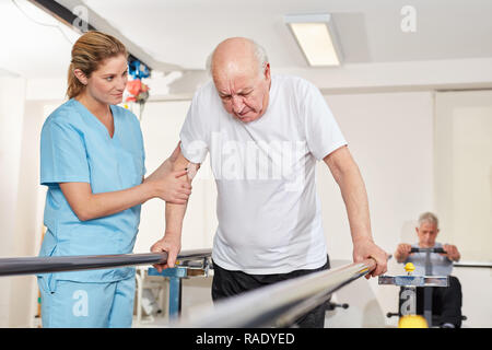 Senior with handicap learns to walk on treadmill supervised by rehab therapist Stock Photo