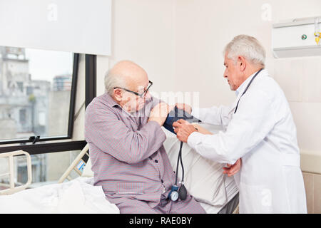 Doctor and senior man measuring blood pressure with blood pressure monitor Stock Photo