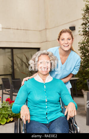 Nurse cares for senior woman in wheelchair in rehab clinic Stock Photo