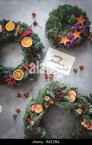 Christmas wreaths handmade from natural materials on a dark background with a handwritten card Stock Photo