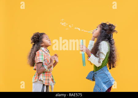 Pleasant afro American girl blowing soap bubbles Stock Photo