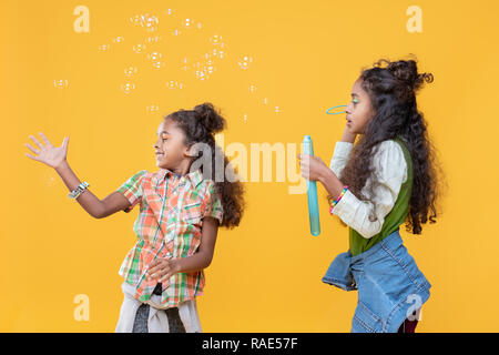 Cheerful happy girl catching the soap bubbles Stock Photo