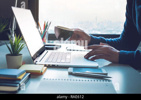Office life concepts with person drinking coffee and using computer laptop on office window view Stock Photo