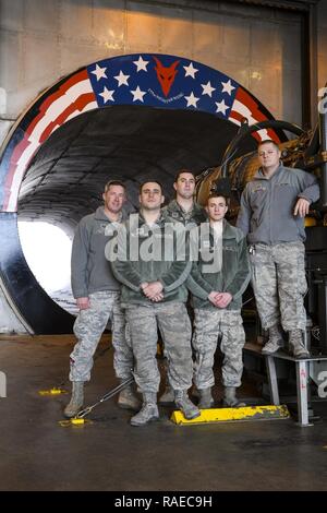 Air National Guardsmen from New Jersey's 177th Fighter Wing, “Jersey Devils”, pose for a photo in front of the morale painting they designed, funded and created at their unit’s engine test cell facility, located at the Atlantic City Air National Guard Base, N.J., on Jan. 31, 2017. The propulsion shop personnel, including two members not shown, wanted to create a feeling of Esprit de Corps and a reminder of just how amazing it is to work on such a complex and important military machine. The General Electric F110-GE-100 turbofan, prepped and ready for testing, produces close to 29,000 pounds of  Stock Photo