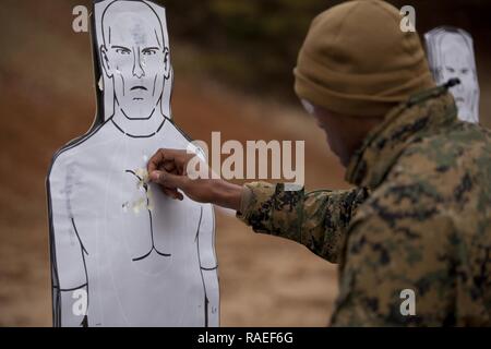 U.S. Marines assigned to The Basic School pasties up his target after conducting the Combat Pistol Program at Weapons Training Battalion (WTBn) aboard MCB Quantico, Va., Jan. 20, 2017.  The purpose of WTBn is to serve as the Marine Corps proponent for all facets of small arms combat marksmanship and to be the focal point for marksmanship doctrine, training, competition, equipment, and weapons. Stock Photo