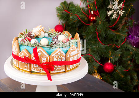 Christmas winter cake with hand made decorating house shape cookies with Christmas tree on the background Stock Photo