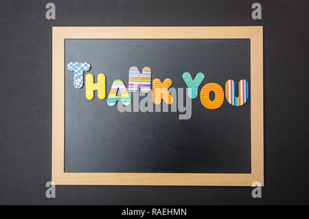 Thank you, Colorful letters shaping the word thank you on blackboard with wooden frame, black wall background Stock Photo