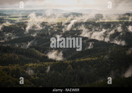 Deadpan dark misty rainy morning landscape with the sand rocky montains in Czech Saxon Switzerland in autumn colors. Stock Photo