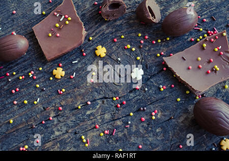 Easter composition with chocolate eggs and pieces of big chocolate egg on old rustic wooden background with place for your text. Happy Easter Holidays Stock Photo
