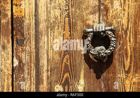 Vintage image of ancient door knocker on a wooden door (In the form of the hand and head of a lion) Stock Photo