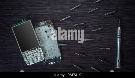 disassembled mobile phone and tools on wooden background Stock Photo