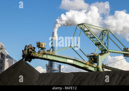 Stacker-reclaimer in a coal handling terminal with in the background a brown coal power plant. Stock Photo
