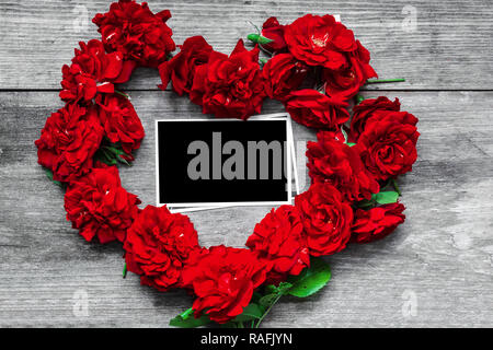 red rose flowers heart shaped with blank photo frame on rustic wooden background. Valentine day concept. top view. mock up Stock Photo