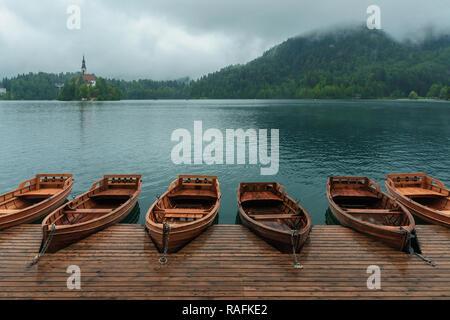 Bled with lake, island, castle, boats and mountains in background in misty and rainy day, Slovenia, Europe Stock Photo