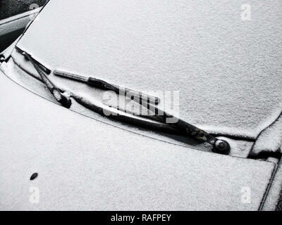 Iced car windshield after snowfall. Snow fell on a warm car. Stock Photo