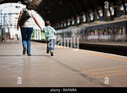 Boy walking with his mum through a train station. Stock Photo