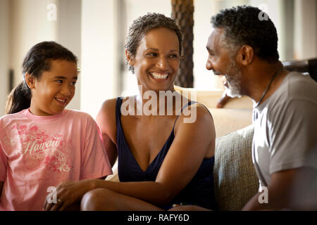Parents laughing with daughter on couch. Stock Photo