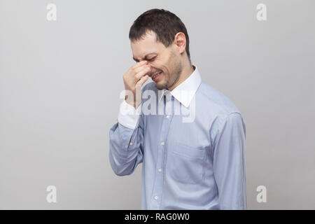 Profile side view portrait of sad lonely handsome bristle businessman in classic light blue shirt standing and crying. indoor studio shot, isolated on Stock Photo