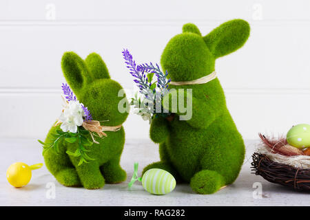 Easter scene with colored eggs in nest and two green bunnies Stock Photo