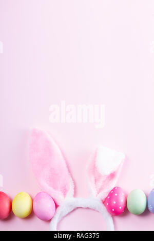 Easter rabbit flaffy ears and colored easter colored eggs on pink and