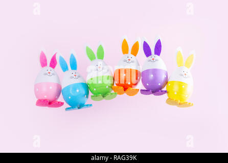 Row of falling funny easter bunnies on plain pink background Stock Photo