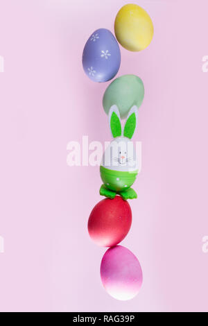 falling funny easter bunnies and colored easter eggs on pink background Stock Photo