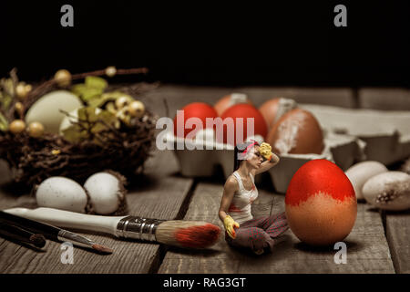 Surreal photo of girl painting big eggs in red on Easter day Stock Photo