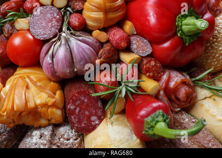 Edible gift to the man, consisting of different varieties of sausage, smoked cheeses, pepper, paprika, tomatoes and black bread. Close-up Stock Photo