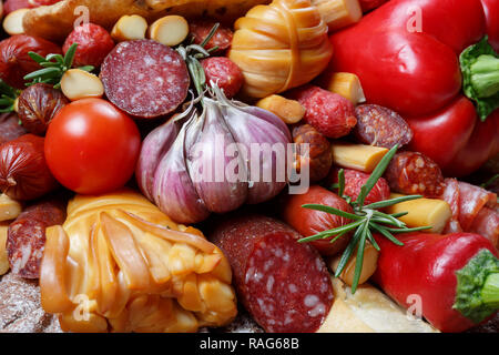 Edible gift to the man, consisting of different varieties of sausage, smoked cheeses, pepper, paprika, tomatoes and black bread. Close-up Stock Photo
