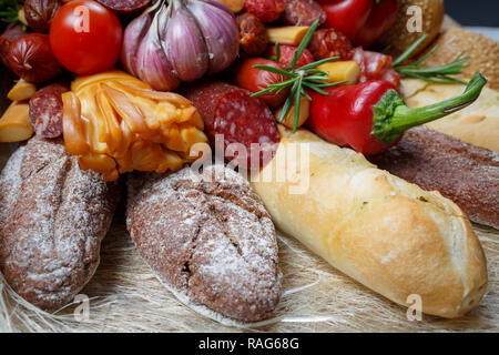 Edible gift to the man, consisting of different varieties of sausage, smoked cheeses, pepper, paprika, tomatoes and black bread. Close-up Stock Photo
