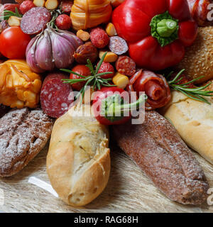 Edible gift to the man, consisting of different varieties of sausage, smoked cheeses, pepper, paprika, tomatoes and black bread. Close-up Stock Photo