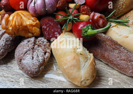 Edible gift to the man, consisting of different varieties of sausage, smoked cheeses, pepper, paprika, tomatoes and black bread. Close-up Stock Photo