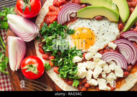 Huevos rancheros breakfast pizza with tomatoes, onion and parsley. Top view. Stock Photo