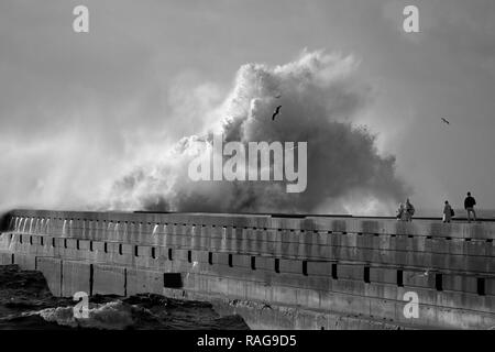 Porto, Portugal - December 31, 2015: Tourists seeing the big stormy sea waves in the Douro river mouth Stock Photo