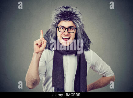 Smiling excited man in winter hat and glasses holding finger up in excitement looking at camera Stock Photo