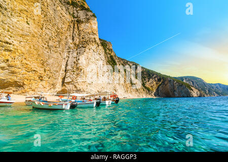 Boats line up at the shoreline in the clear waters off the sandy Paradise Beach or Chomi Beach on a sunny day in Corfu Greece. Stock Photo