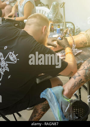 Tattoo artist makes a tattoo on a man's hand. Stock Photo