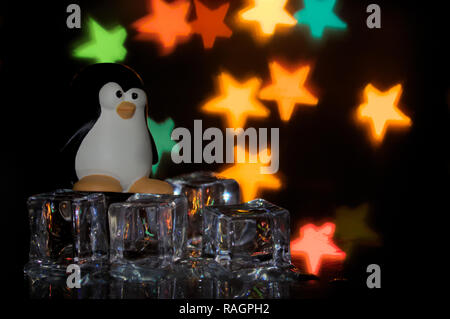 The penguin emblem of free software, Tux, on ice cubes with multicolored stars in the background Stock Photo