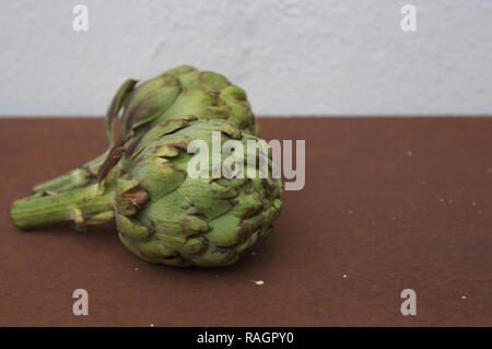 Two side artichokes with space to place some text on a rusty surface with vintage air and light background Stock Photo