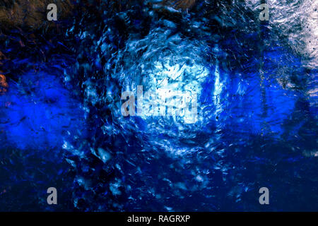 Clear transparent ice with small bubbles illuminated with white and blue light. The structure of the ice creates fantastic patterns. Stock Photo