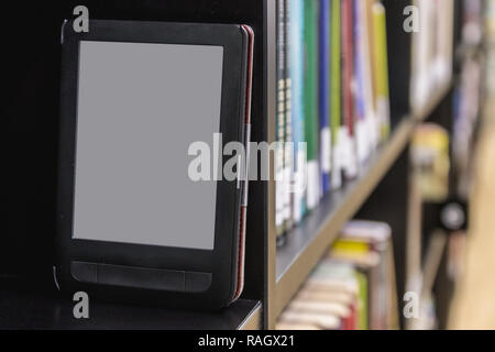 The electronic book on a bookshelf among the many books in the l Stock Photo