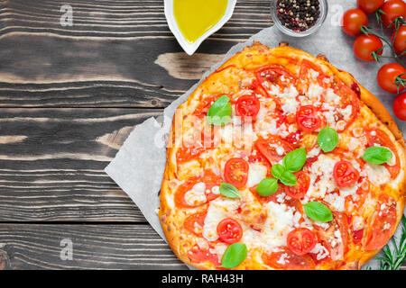 Pizza Margherita with tomatoes, basil and mozzarella cheese over rustic wooden background. top view with copy space Stock Photo