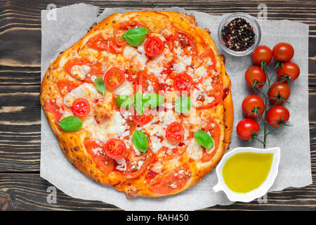 Margherita Italian pizza with melted mozzarella cheese, tomato and fresh basil on rustic wooden table. top view Stock Photo