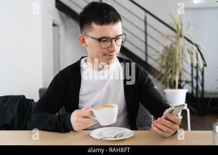 Handsome man having coffee and using smartphone at coffee shop Stock Photo