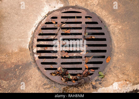 Centered circular grated drain cover on a cement street surface. Stock Photo