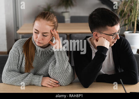 Angry unhappy young couple ignoring not looking at each other after family fight or quarrel, upset thoughtful spouses avoiding talk, sitting silently on couch, having relationship troubles Stock Photo
