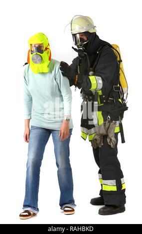 Firefighter wearing respiratory protective equipment with a person wearing an emergency smoke hood that is used to evacuate Stock Photo