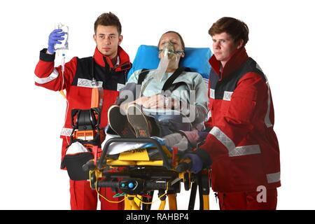 Paramedics recuscitating a patient and giving them an infusion on a wheeled stretcher, professional firefighters from the Stock Photo